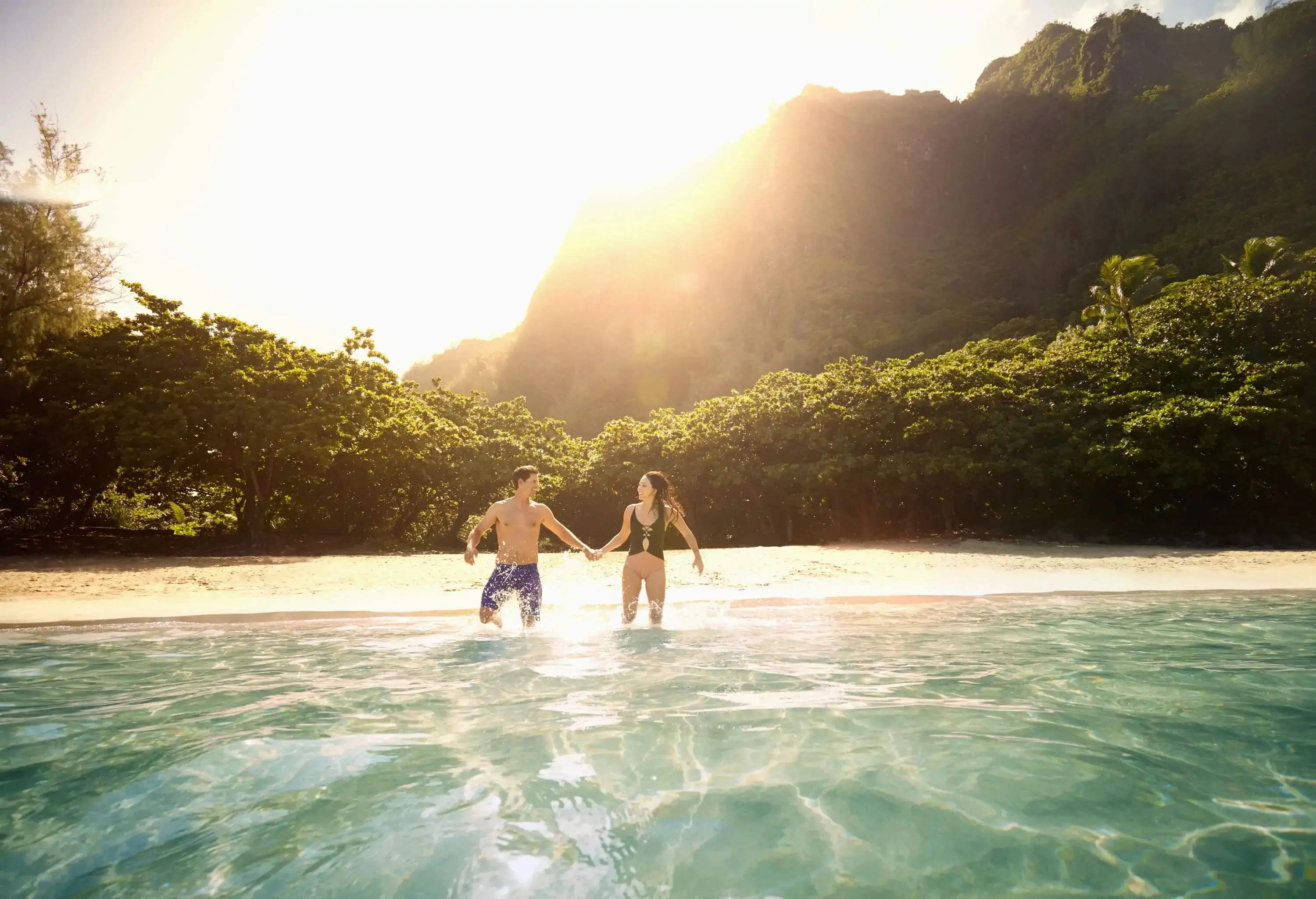 Couple running into the sea from a tropical deserted beach