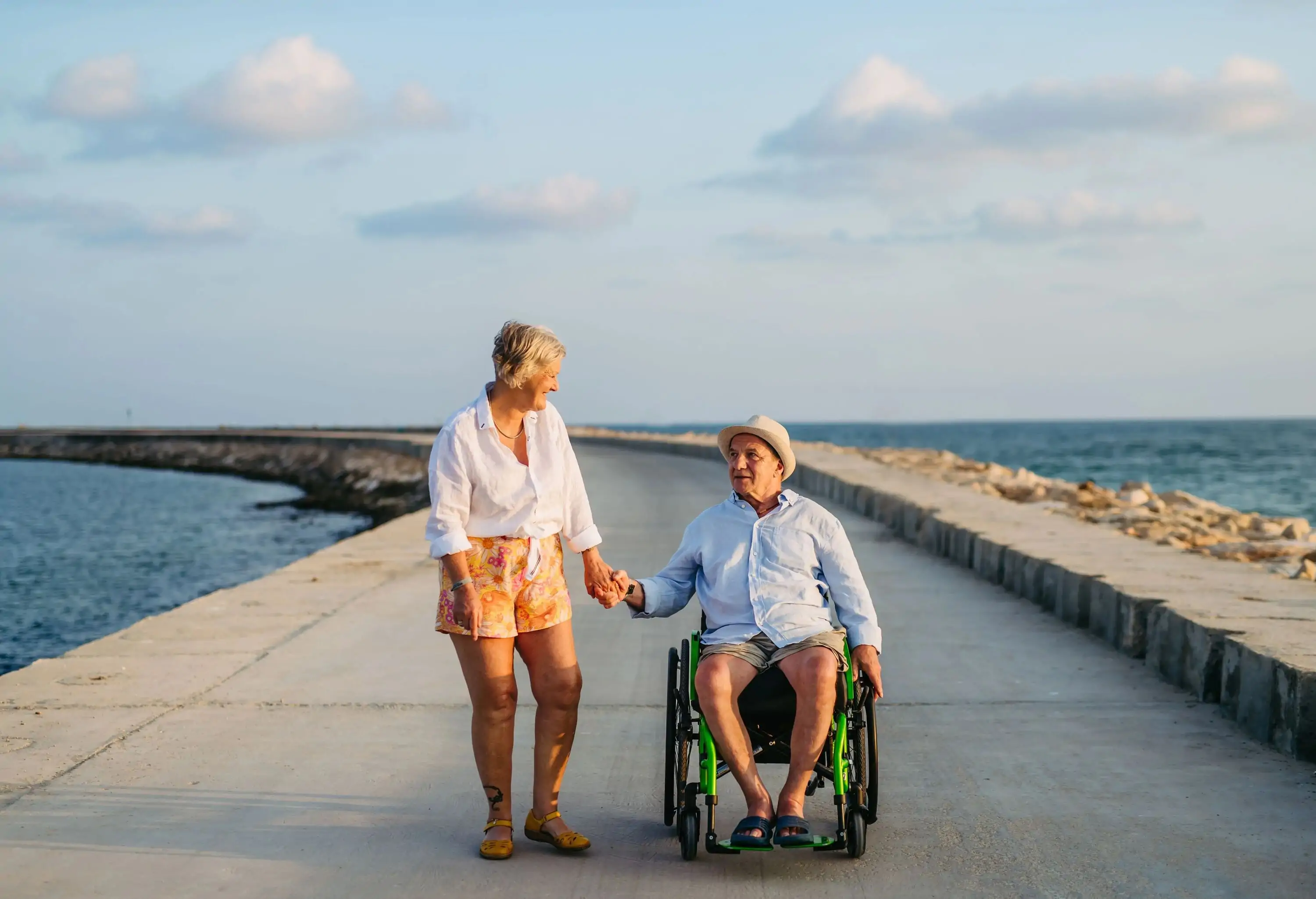 Senior woman with her husband on wheelchair enjoying holiday at sea.