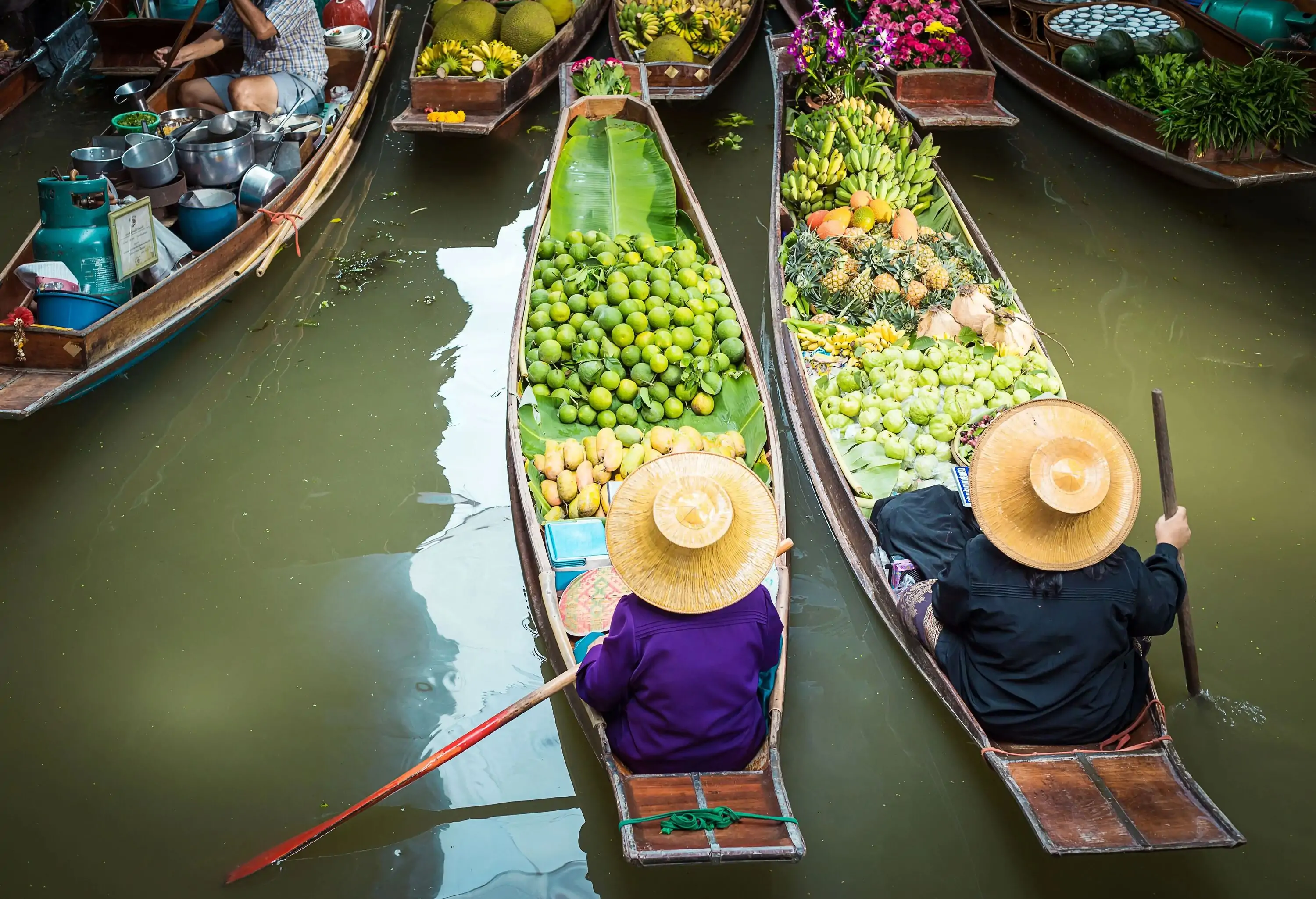 Floating market in Thailand, two sellers side by side on their boat full of fruit