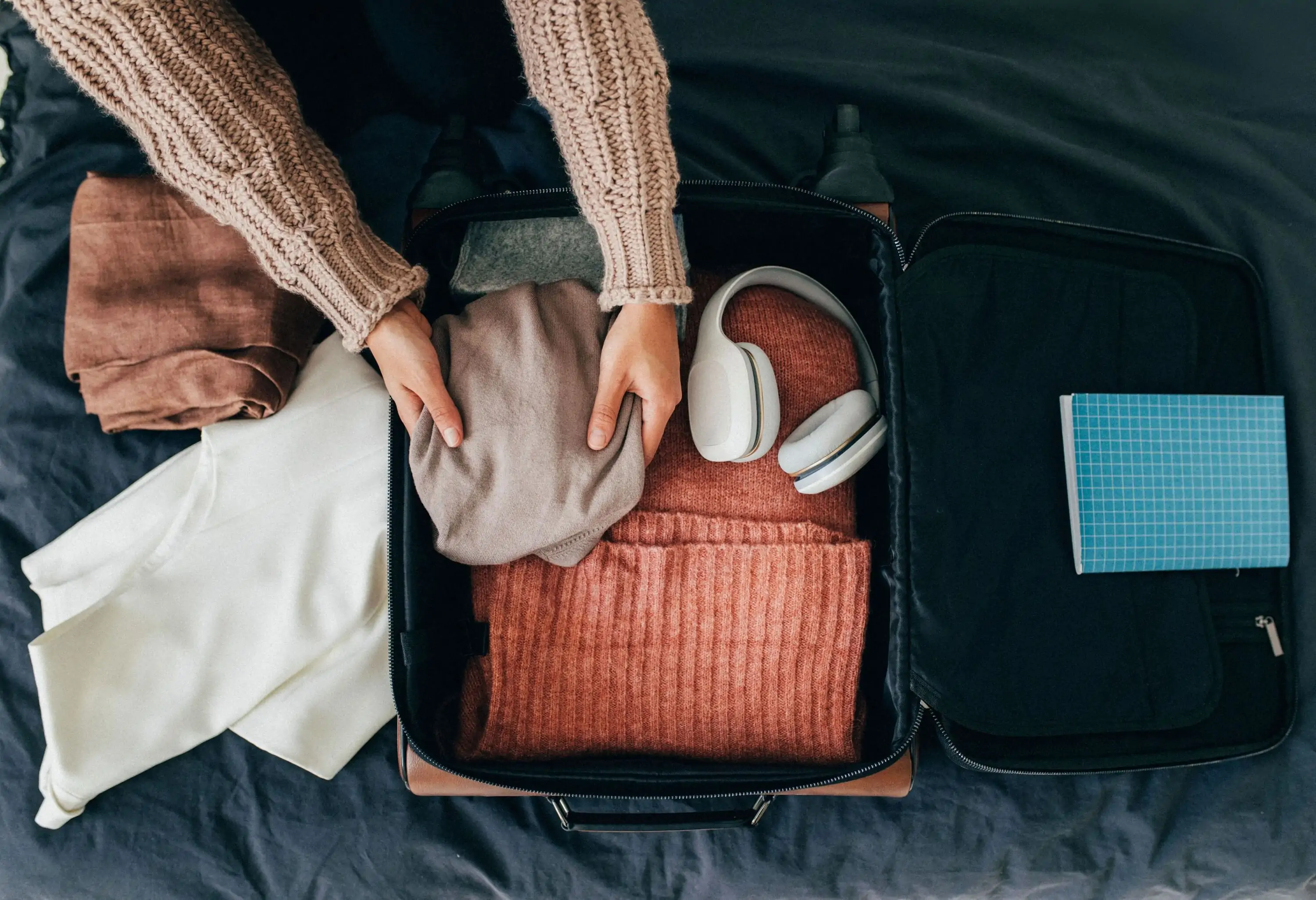 A women putting all travel essentials into a carry-on suitcase