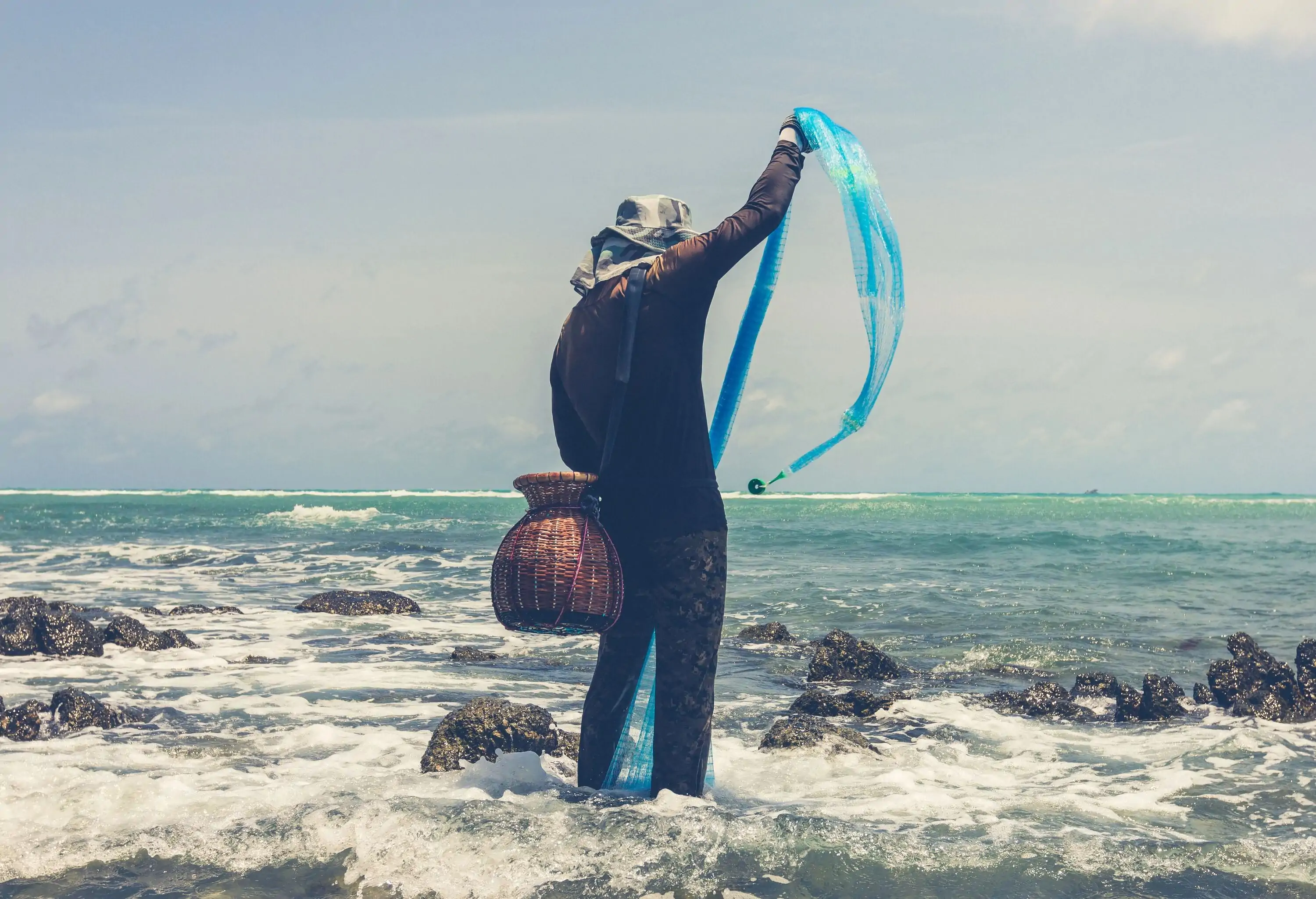 Local fisherman stretching fish net to catch fish in the sea during low tide at Bang Tao Beach, Phuket, Thailand. Thai way of life