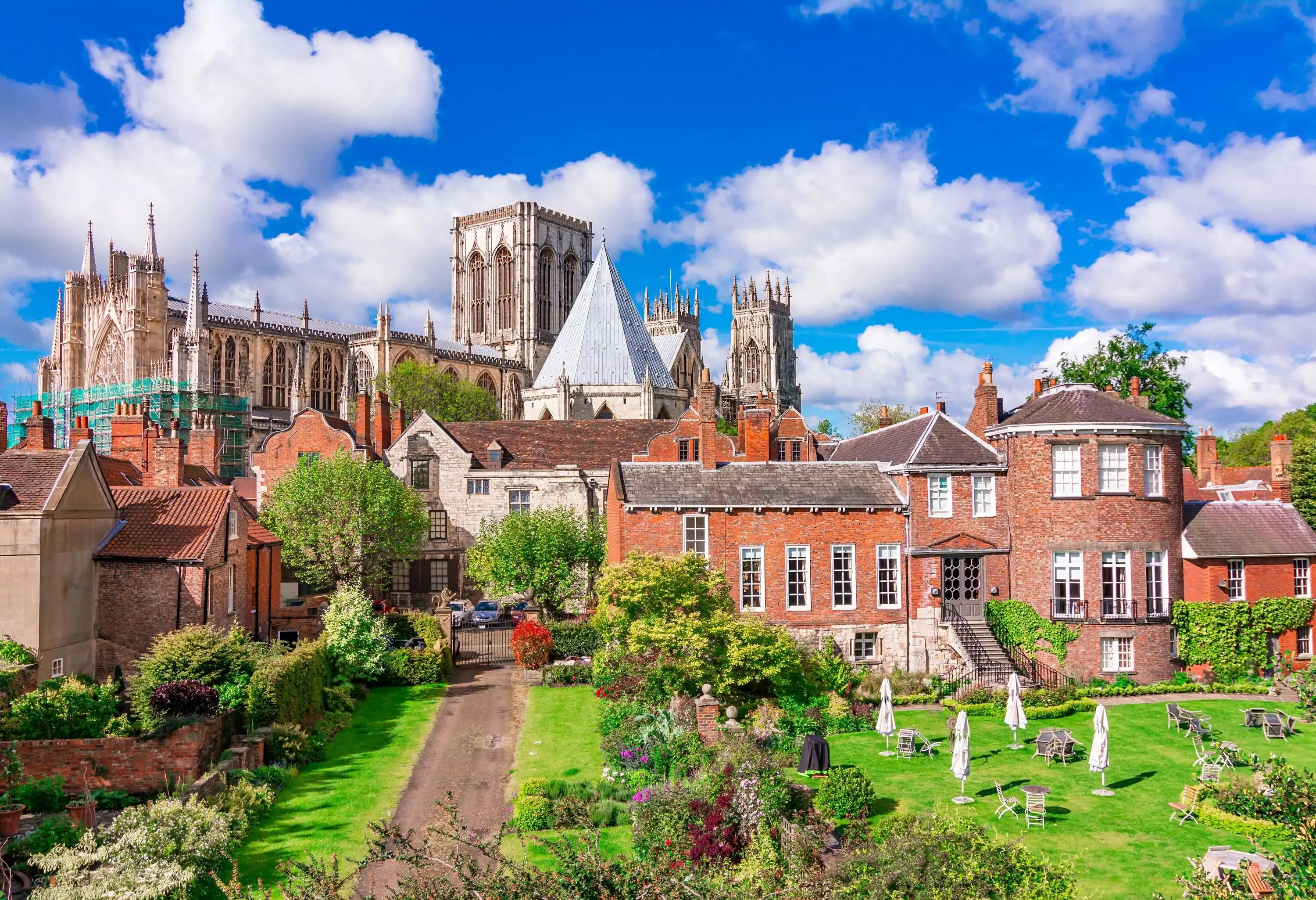 Behind a small lovely neighbourhood is a large cathedral with its towers and spires visibly seen.