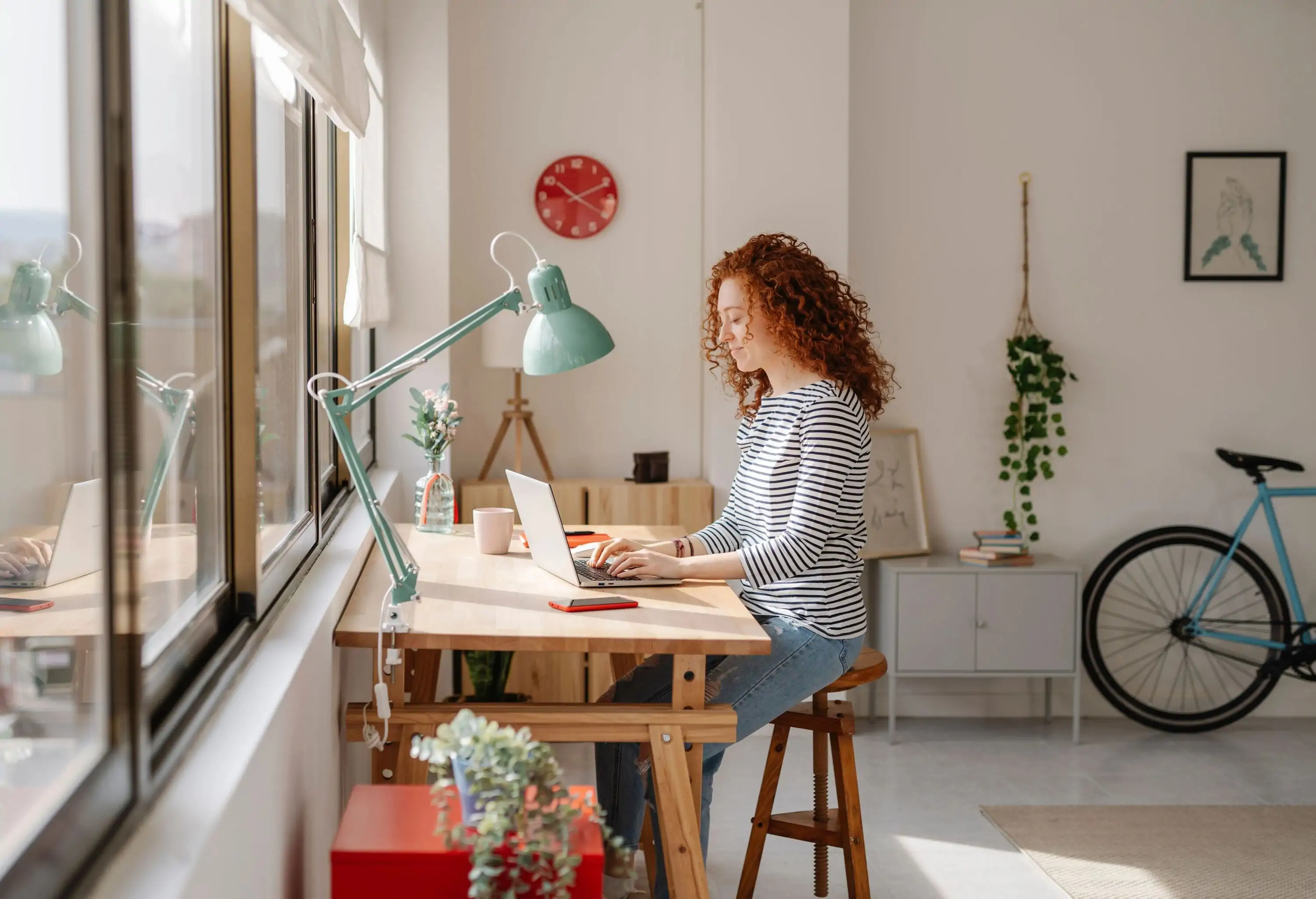 Woman sitting on a desk using a laptop computer while working from home. Business, freelance and home office concept.