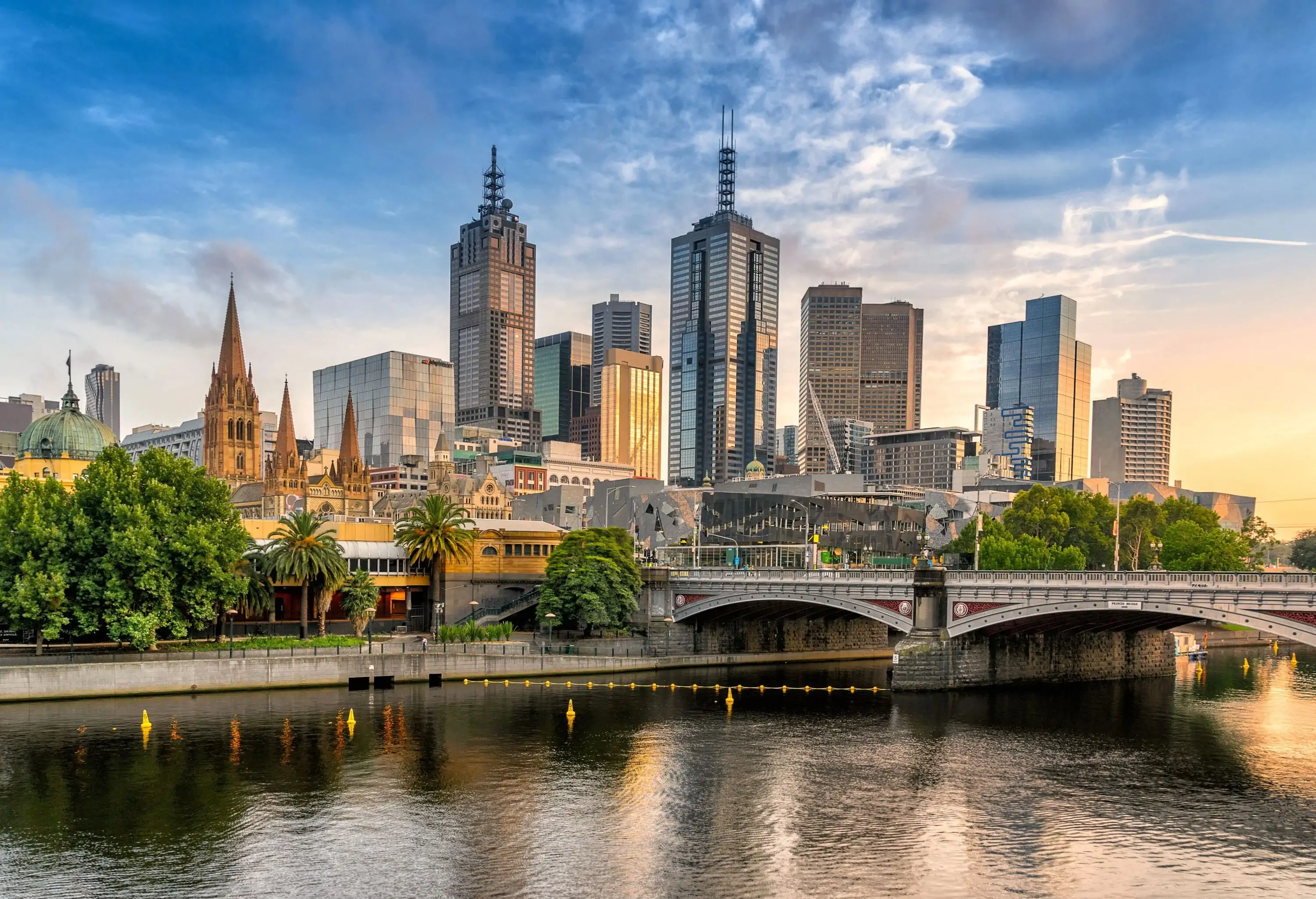 Contemporary soaring buildings and pointed spires by the riverbank towering to the sky.