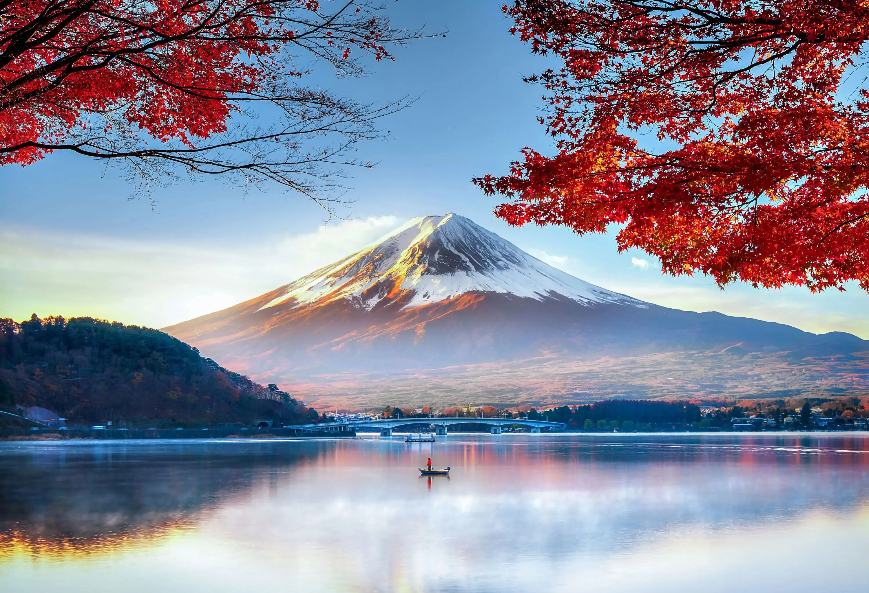 An iconic snow-capped mountain with its reflection on a lake in autumn