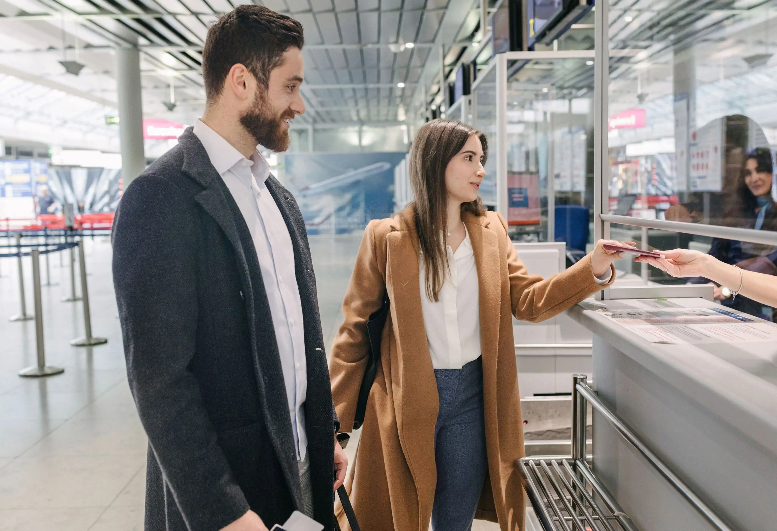 A well-dressed couple interacting with the border control guards at an airport and showing their passports as arrive at a new country together.